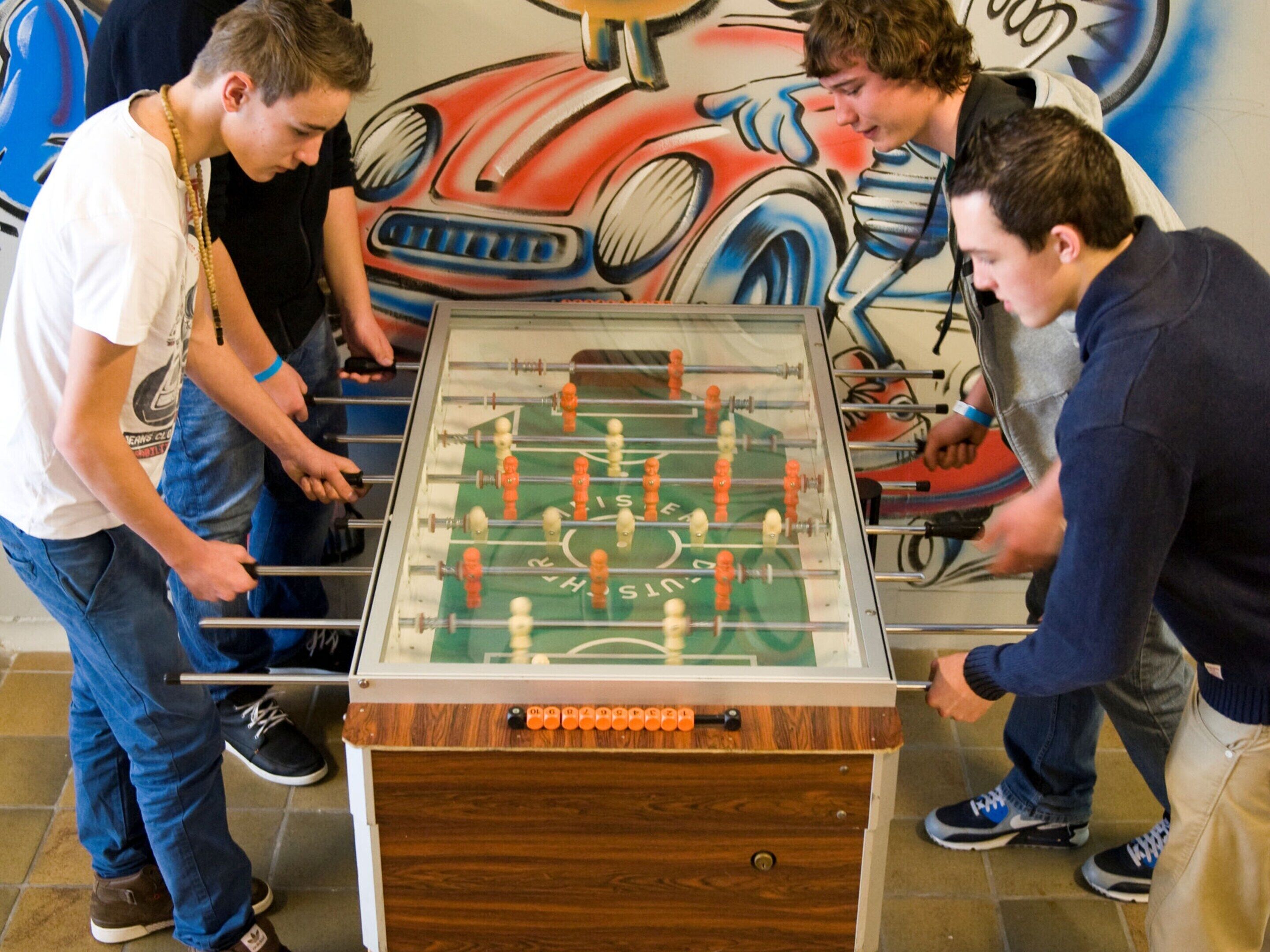 A foosball table in a room with a mural on the wall.
