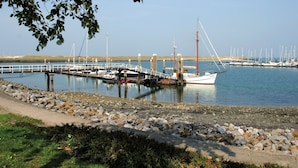 Un puerto deportivo con barcos amarrados, un muelle de madera y un litoral rocoso.