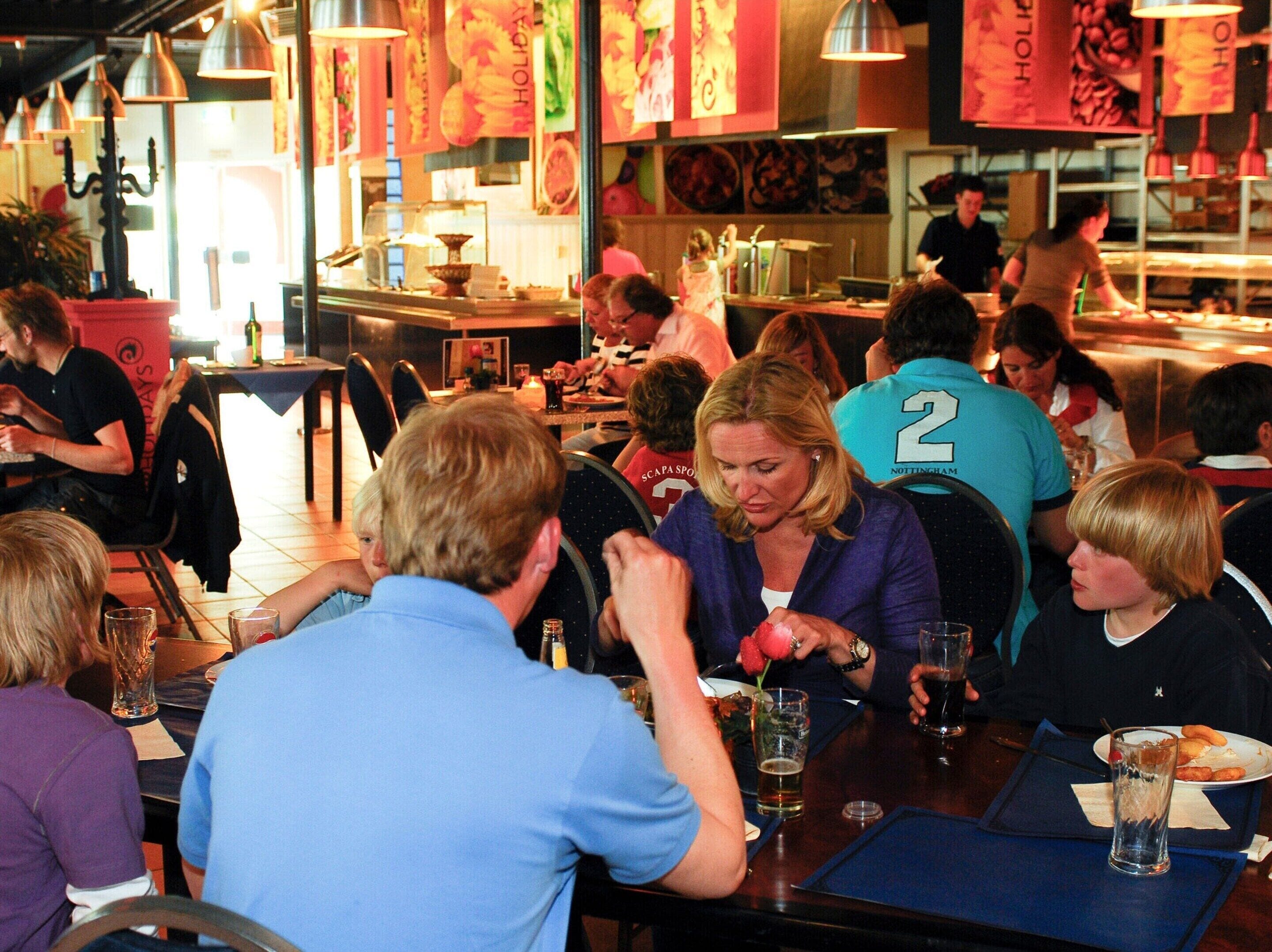 A busy restaurant with patrons seated at tables, some with drinks and food.