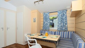 Habitación compacta con una mesa de comedor, sillas, un banco y una ventana con cortinas.