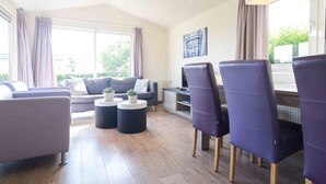 Een moderne woonkamer met een bank, twee fauteuils, een salontafel en een televisie.