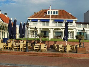 A building with a balcony, outdoor seating, and a flag. - Comfortable Chalet With Dishwasher in Noordwijk near the Sea (Noordwijk)