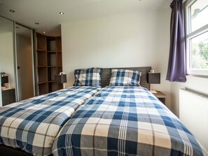 A bedroom with a bed, a wardrobe, and a window with curtains.