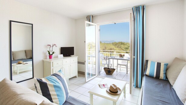 A room with a bed, a TV, a dining table, and a balcony with a view. - Spacious Apt Near the Beach (Fréjus)