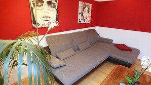 A living room with a grey sofa, a red wall, and a wooden coffee table. - Gemutliche Wohnung in Schwenningen (Villingen-Schwenningen)