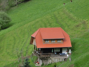 A house with a red roof, a wooden porch, and a stone foundation.