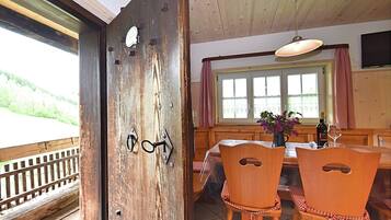 A wooden door with a rustic design, a dining area with a table and chairs, and a window with curtains.