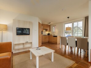 Relax in a spacious living area with a flat-screen TV, comfortable seating, and a dining table for four.