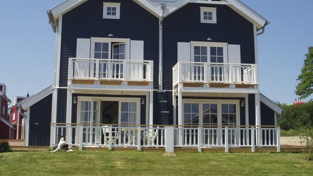 A two-story building with a balcony on each floor, white railings, and a clear sky. - Holiday Home by the Sea With Sauna (Sierksdorf)