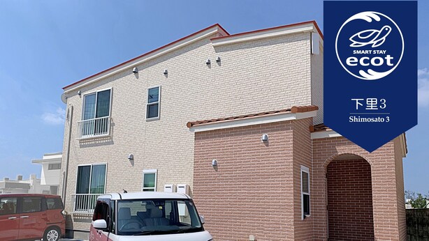A two-story building with a brick facade and a small attached garage. - Ecot Shimozato 3 (Miyakojima)
