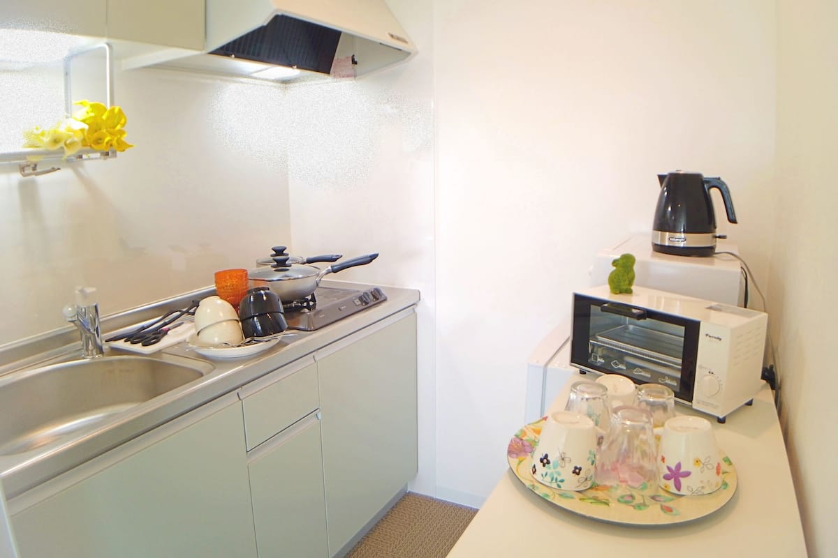 A compact kitchen with a sink, stove, and a toaster oven.