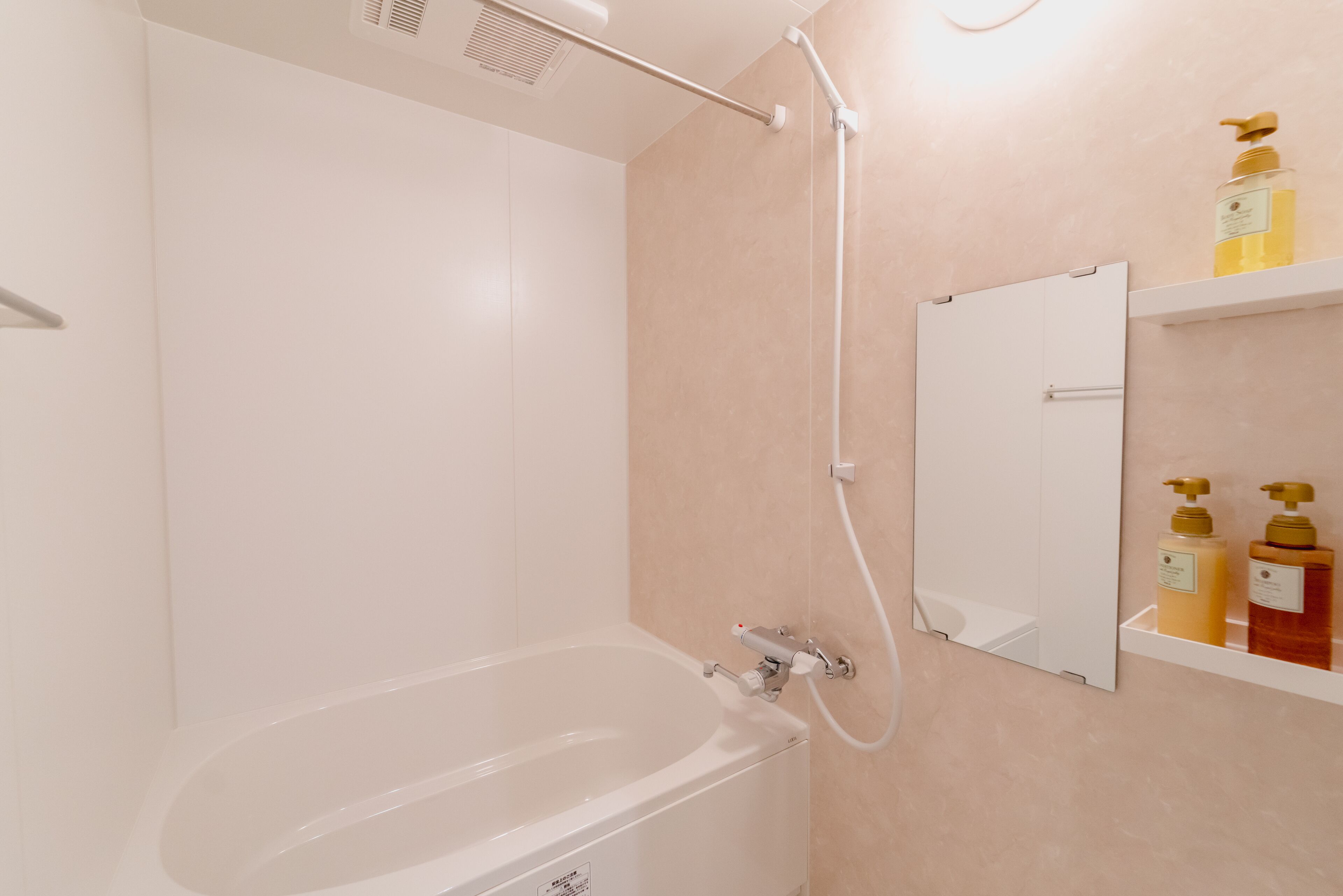 Een moderne badkamer met een wit bad, een handdouche en een spiegel aan de muur.