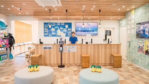 A reception area with a wooden counter, a large map on the wall, and two round seating areas with plush toys. - Ecot Shimozato 3 (Miyakojima)