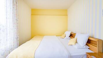 Una cama bien hecha con ropa de cama blanca y beige, un cabecero de madera y una mesita de noche con una lámpara.