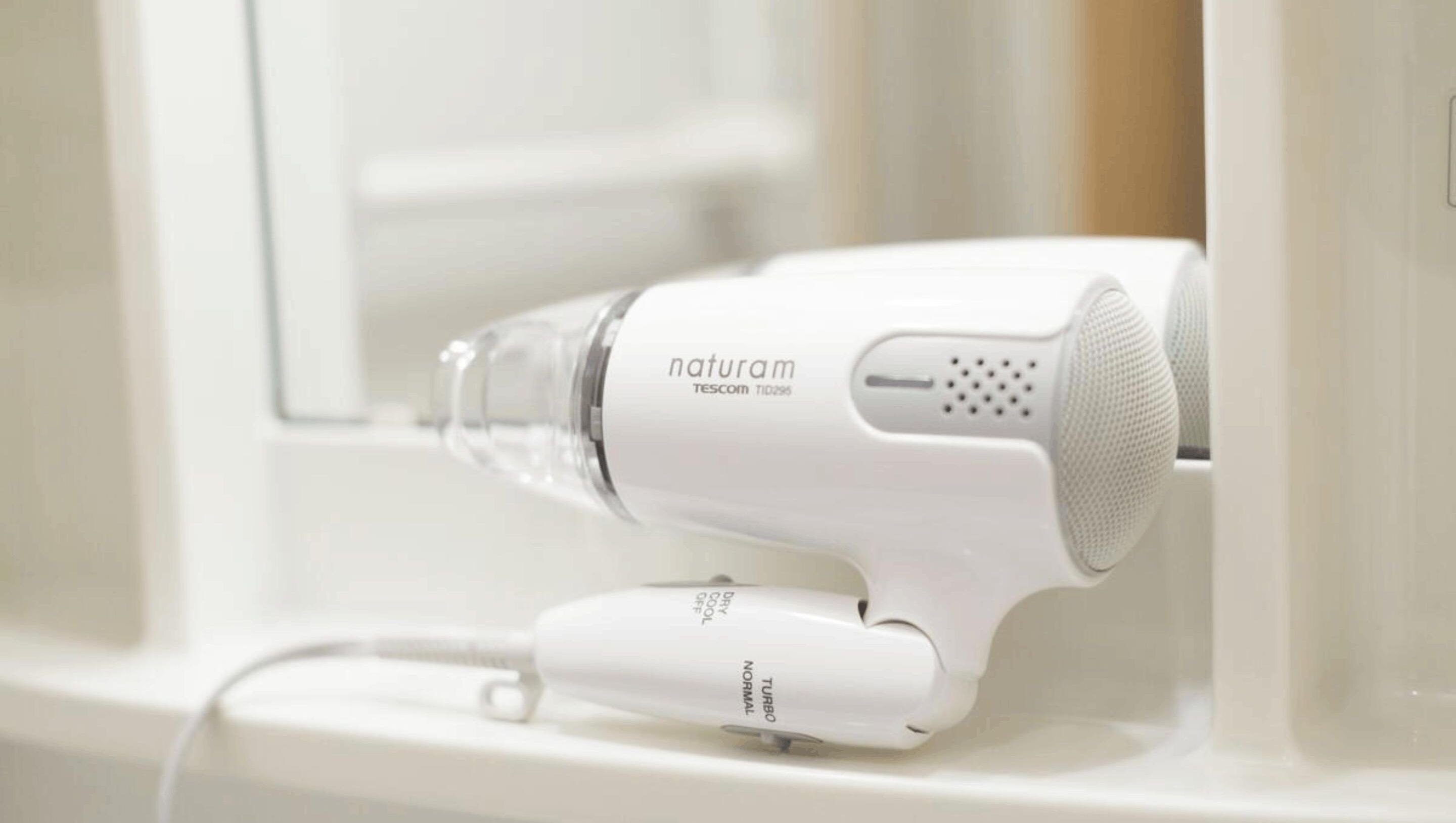 Een witte haardroger met bedieningspaneel, geplaatst op een wit oppervlak.