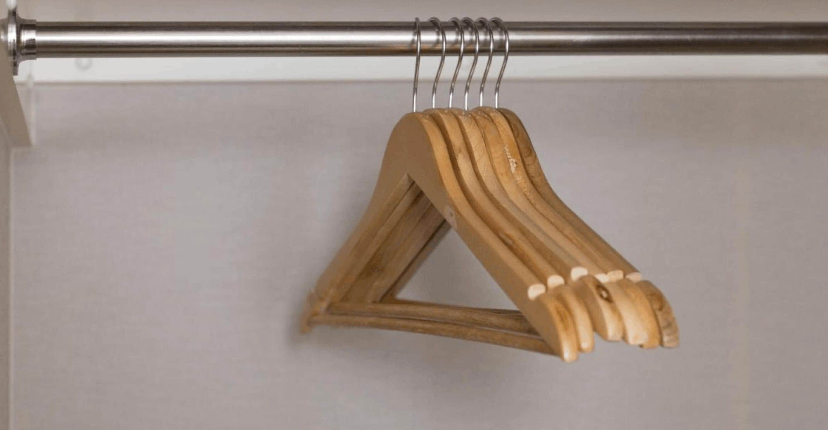 A wooden hanger with a triangular base and a curved handle, hanging on a metal rod.