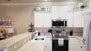 Una cocina moderna con armarios blancos, electrodomésticos de acero inoxidable y un diseño limpio.