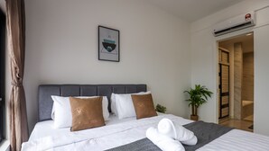 A neatly made bed with white linens and two decorative pillows, a framed artwork above the bed, a potted plant beside the bed, and a visible air conditioning unit on the wall. - Imperio Seaview Melaka By I Housing (Malacca City)