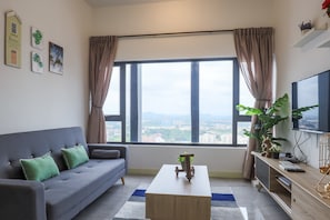 Una sala moderna con un sofá gris, una mesa de centro y un ventanal con cortinas.