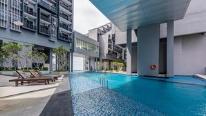 A modern building with a rooftop pool, lounge chairs, and a clear blue sky. - Imperio Seaview Melaka By I Housing (Malacca City)