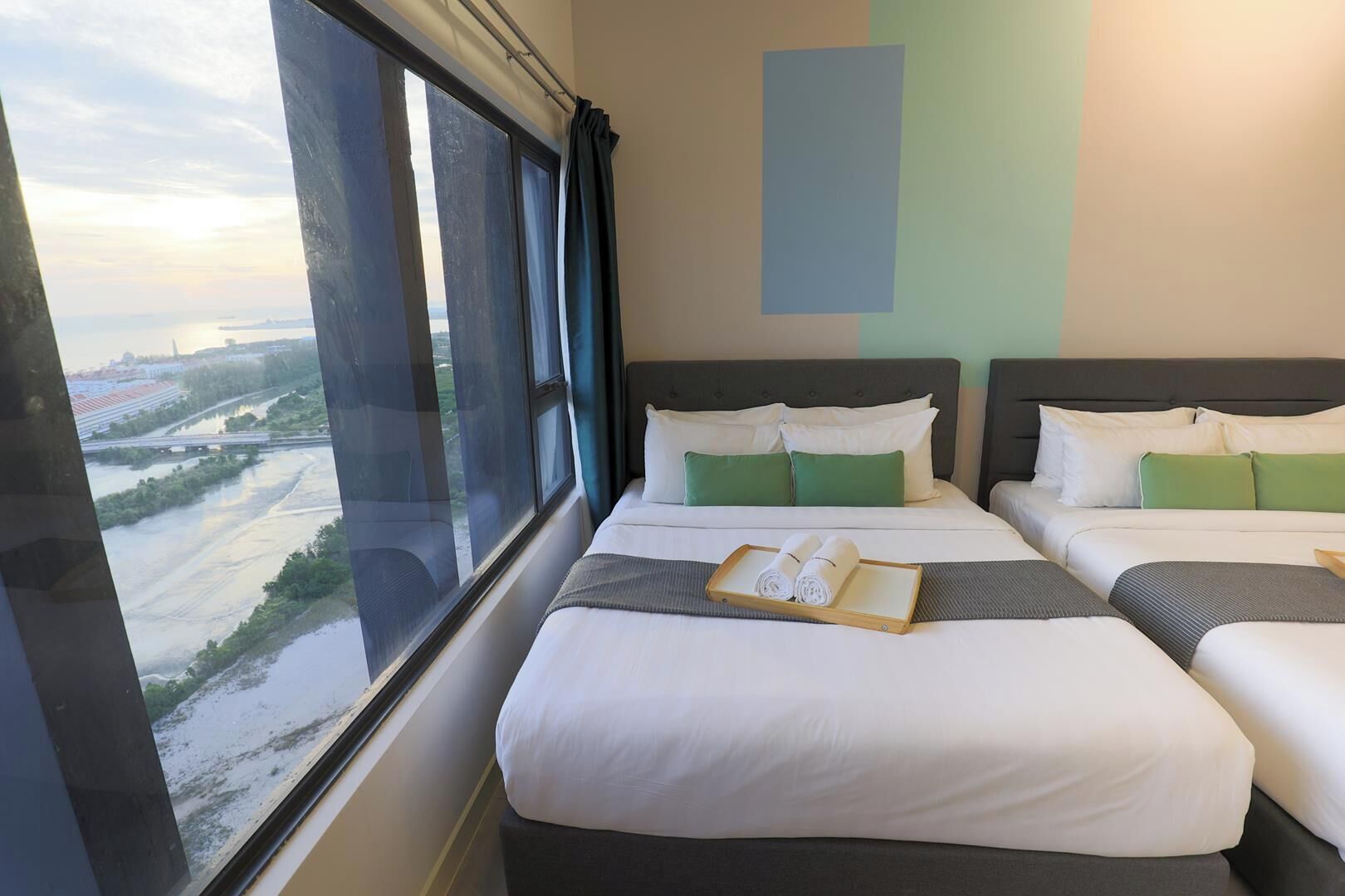 A hotel room with two beds, a view of a river and bridge, and a window with curtains.