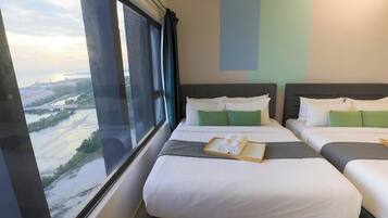 A hotel room with two beds, a view of a river and bridge, and a window with curtains.