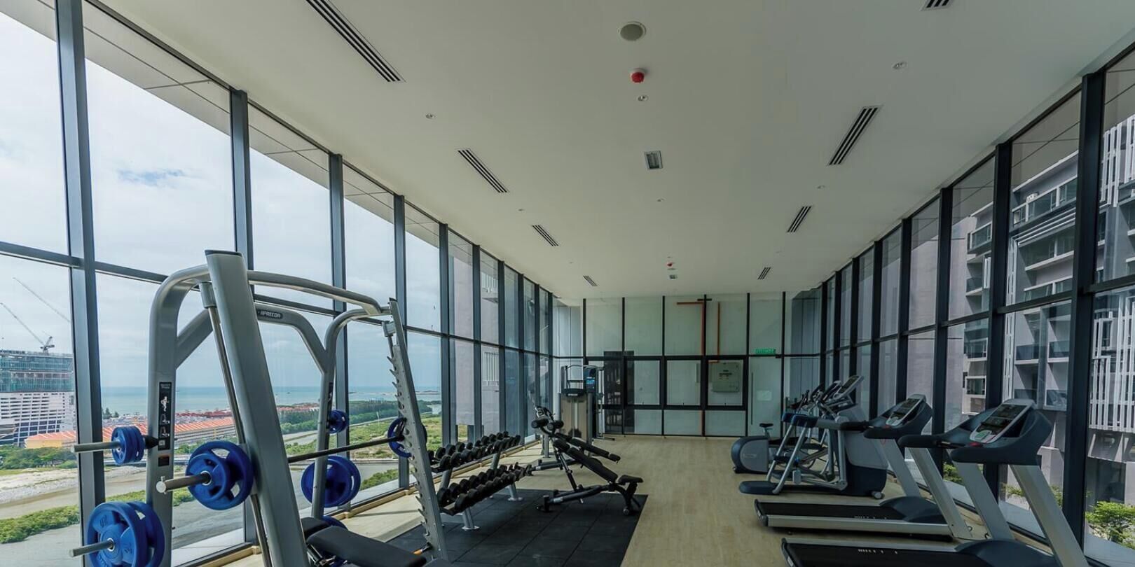 A gym with exercise equipment, large windows, and a view of a cityscape.
