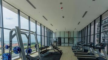 A gym with exercise equipment, large windows, and a view of a cityscape.