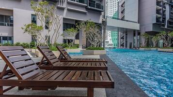 Un hotel moderno con piscina, sdraio e vista sugli edifici circostanti.