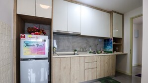 A modern kitchen with a built-in refrigerator, wooden cabinets, and a stainless steel range hood. - Imperio Seaview Melaka By I Housing (Malacca City)