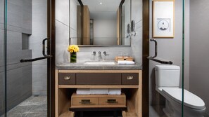 A modern bathroom with a marble sink, wooden vanity, and a toilet.