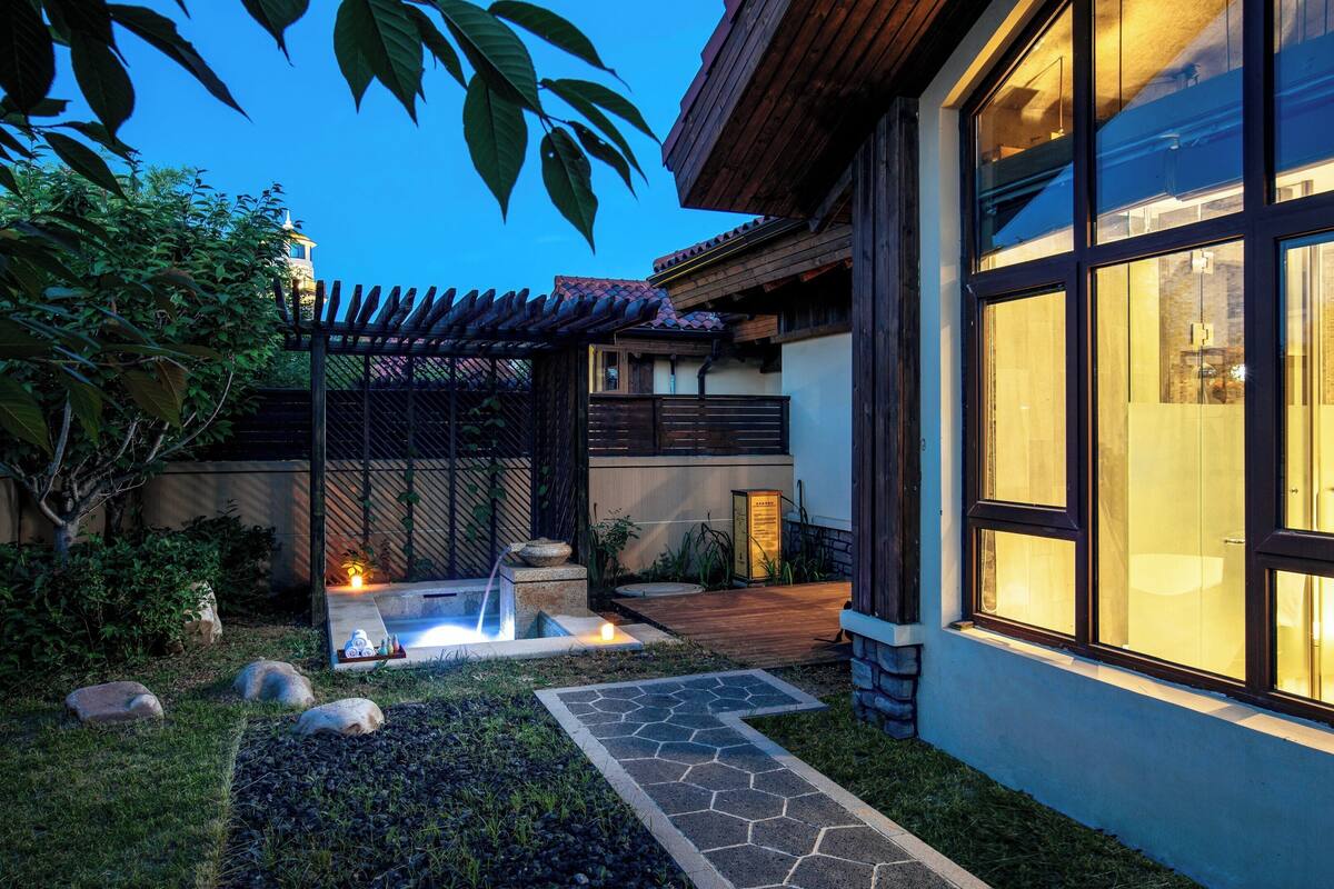 A modern house with a stone pathway leading to a small garden area with a fire feature.