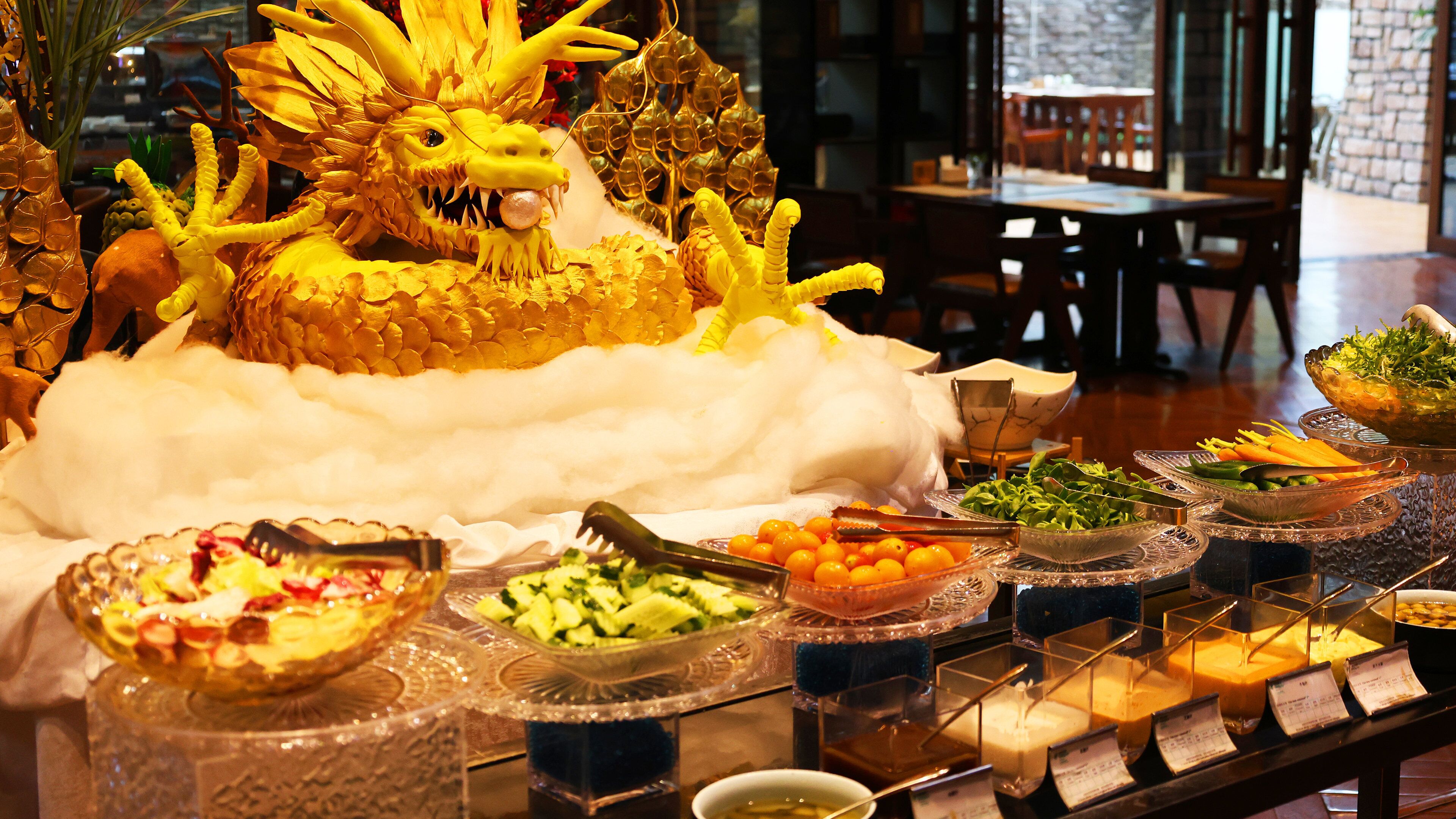 A buffet table with various food items and a decorative dragon centerpiece.