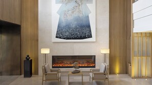 A modern lobby with a large abstract painting, a fireplace, and two armchairs.