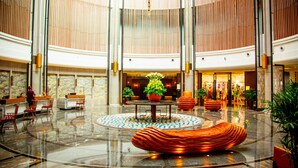 A spacious lobby with a reception desk, seating area, and a central decorative feature. - Holiday Inn Dalian Hot Spring by IHG (Dalian)