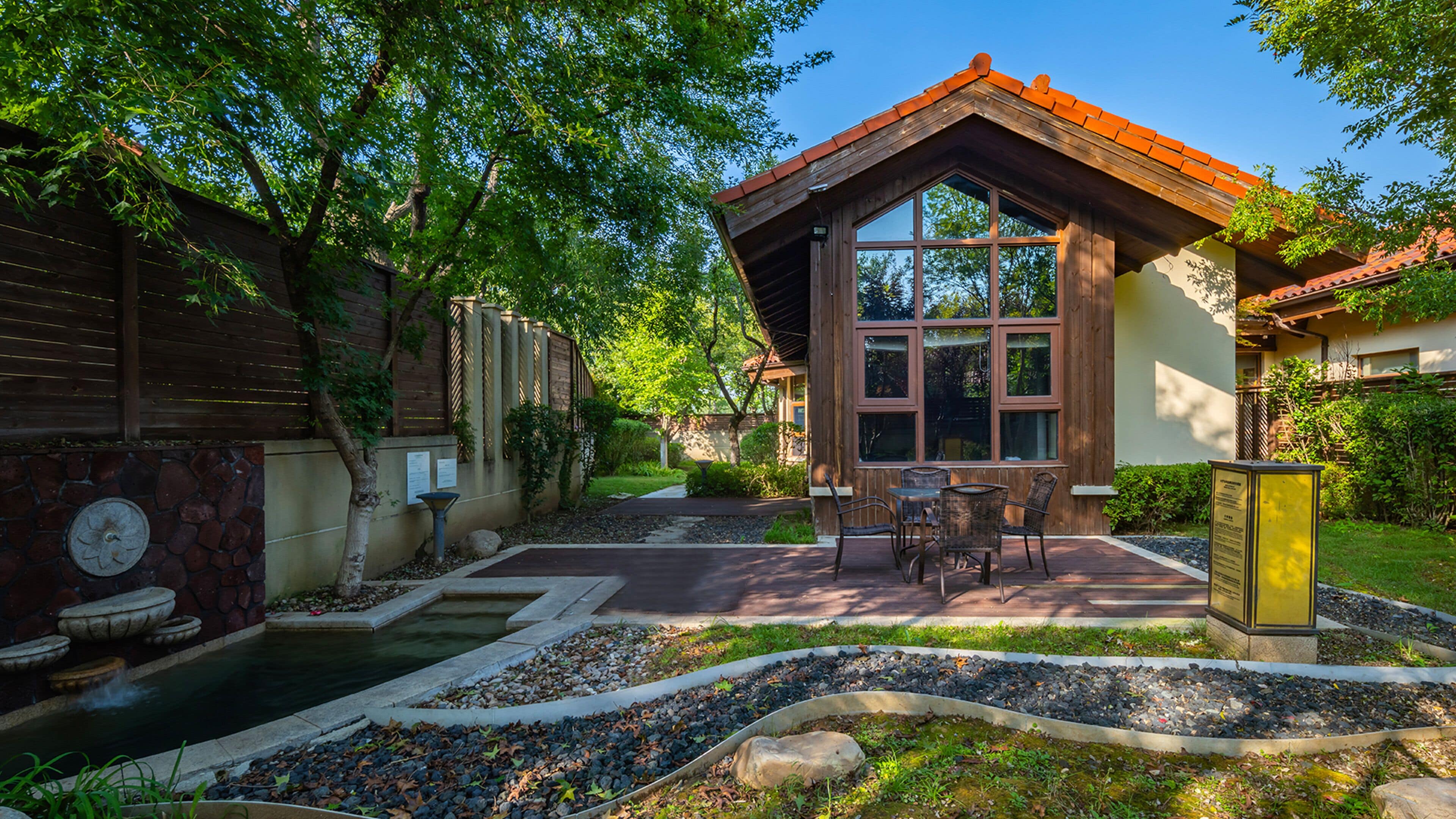 Una casa con patio, una fuente de piedra y un jardín con estanque.