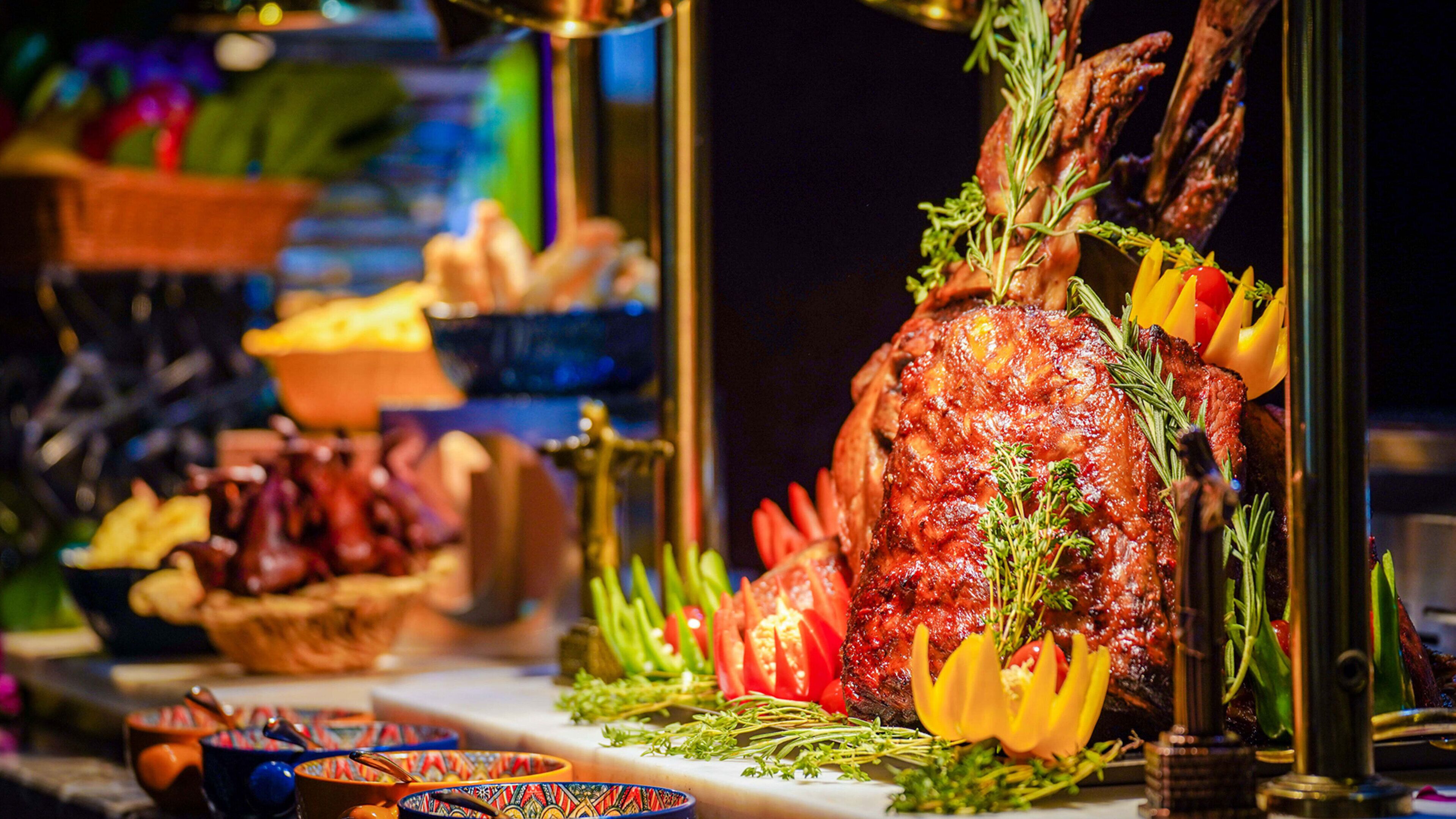 Un buffet proposant une variété de plats, dont un grand plat de viande rôtie, agrémenté d’herbes et de légumes.