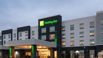 A Holiday Inn hotel with a modern facade, a large parking lot, and a well-lit entrance.