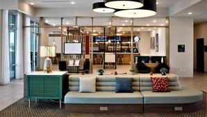Un moderno vestíbulo de hotel con zona de estar, un bar y un comedor.