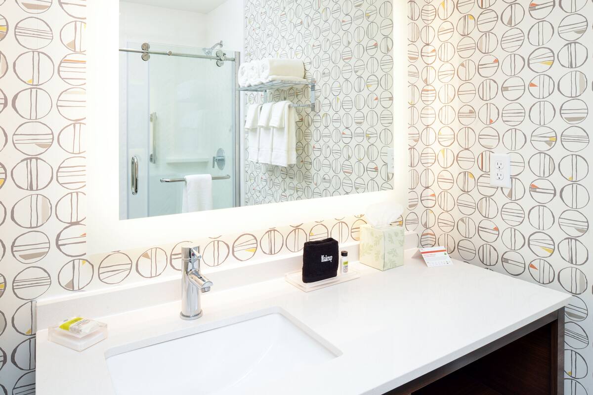 A bathroom with a white sink, a mirror, and a shower area.