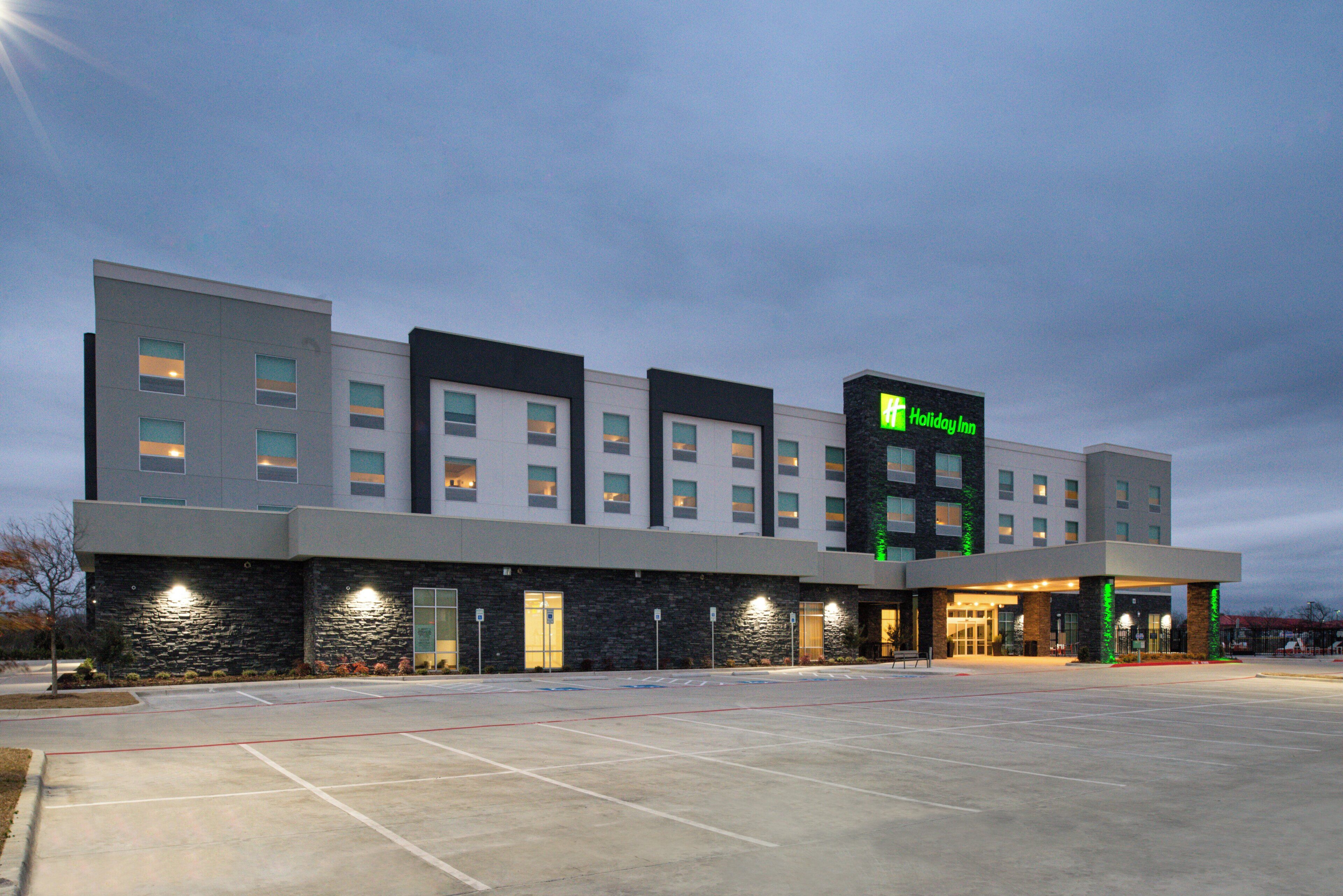 A Holiday Inn hotel with a modern design, featuring a flat roof, multiple windows, and a well-lit entrance.