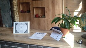 A reception desk with a wooden backdrop, a potted plant, and a calendar. - ATRIUM Guesthouse (Riga)