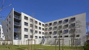 A modern multi-story residential building with balconies, a grassy courtyard, and a clear blue sky. - Nemea Beaux arts (Montpellier)
