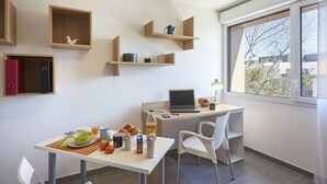A modern kitchen with built-in shelves, a dining table with breakfast items, and a laptop on a desk. - Nemea Beaux arts (Montpellier)