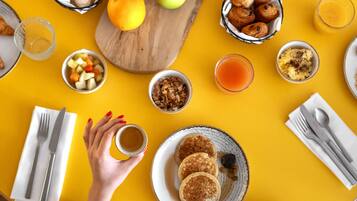 A breakfast table with various food items and a cup of coffee.