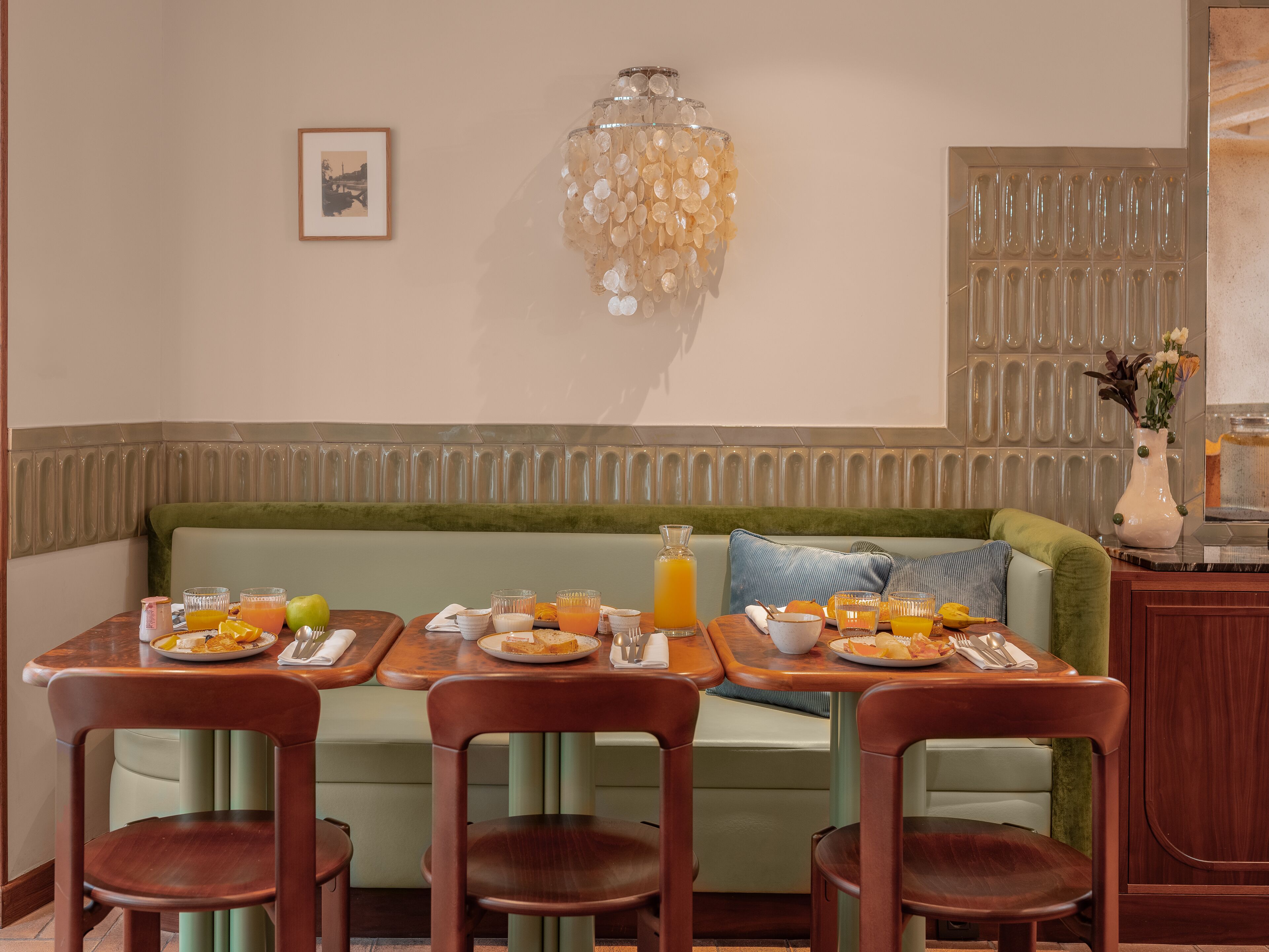 A dining area with a green sofa, wooden chairs, and a table set with breakfast items.