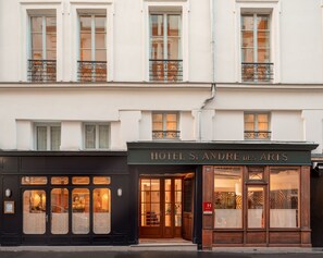 A hotel facade with a classic European architectural style, featuring large windows and a prominent entrance. - Hotel Saint André des Arts (Paris)