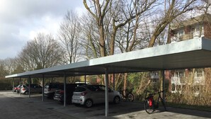A covered parking area with several cars and bicycles. - Boardinghouse Oelde - Apartment mit Terrasse (Oelde)