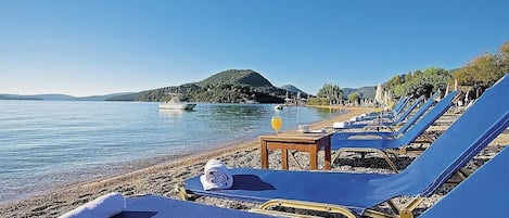 Na praia, espreguiçadeiras, guarda-sóis, bar na praia