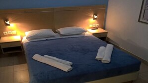 Ein ordentlich gemachtes Bett mit blauer Bettwäsche und weißen Kissen, zwei Nachttische mit Lampen und ein gerahmtes Bild an der Wand.